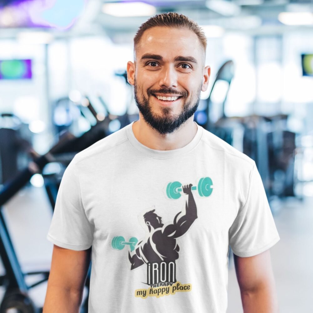 smiling man in gym wearing a tshirt printed with muscle man lifted dumbells and quote iron therapy is my happy home